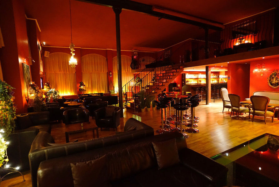 Der grosse Saal der Orangerie: Kronleuchter, Bogenfenster und die beleuchtete Bar